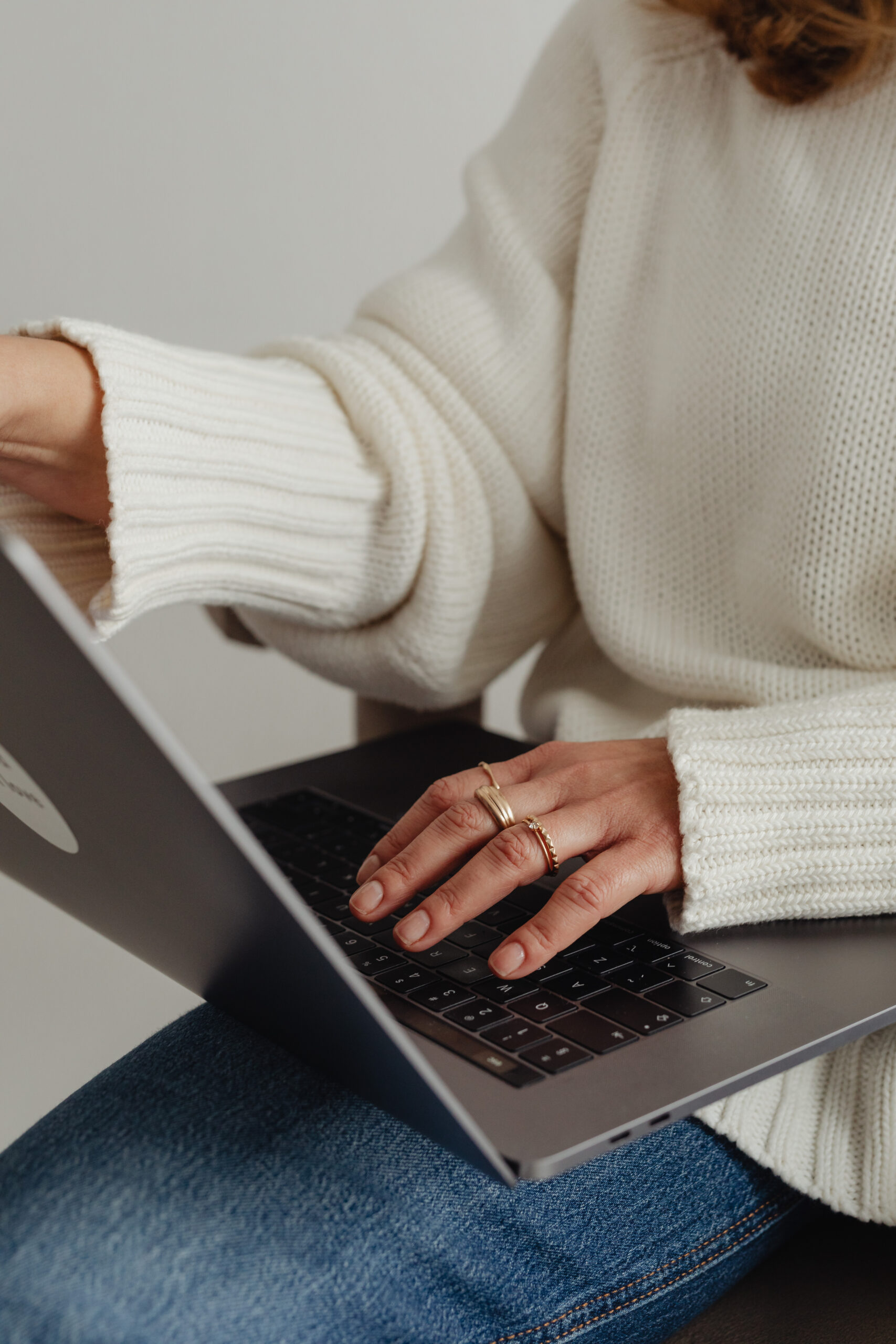 Woman is sitting while typing on a laptop that's placed on her legs.